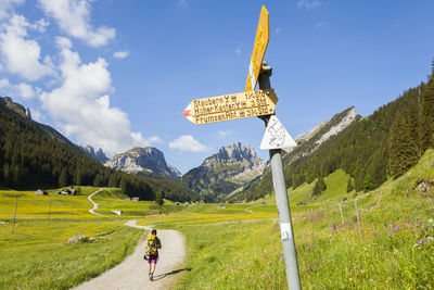 Hiker and trail sign on dirt road in alpstein, appenzell, switzerland