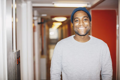 Portrait of happy man standing in college dorm corridor