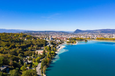 High angle view of townscape by river against blue sky