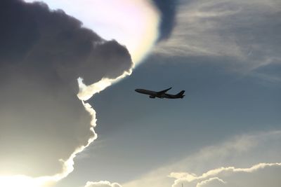 Low angle view of silhouette airplane flying against sky