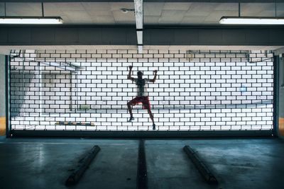 Man climbing on metal grate of window