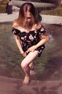 Full length of young woman standing in fountain