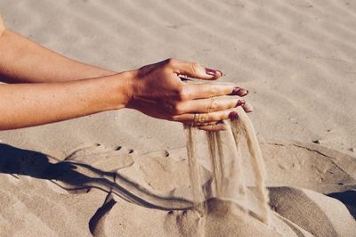 Low section of woman on sand at beach