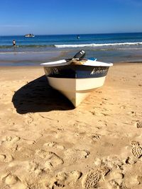 Boat moored on beach against clear sky