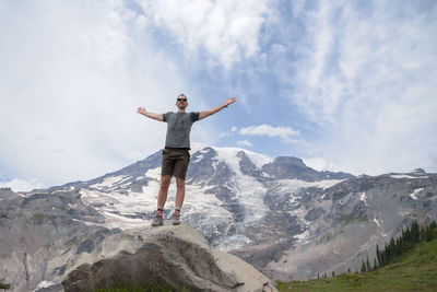 Low angle view of man standing on mount rainier against sky