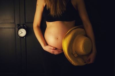 Midsection of woman standing against black background