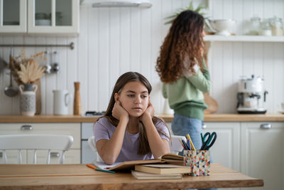 Young woman using mobile phone while sitting on table