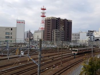 Railroad tracks amidst buildings in city against sky