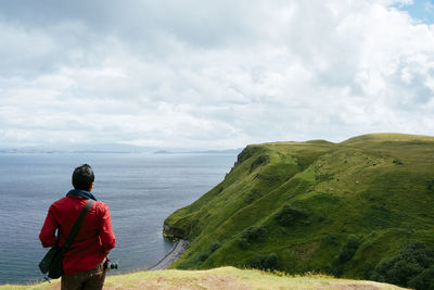 Rear view of man standing by sea against sky