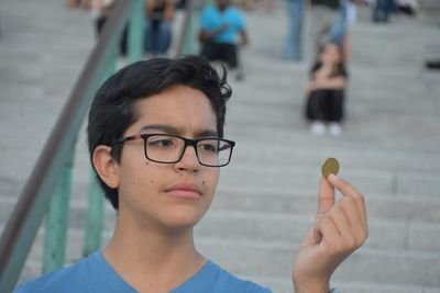 Close-up of boy holding coin against steps in city