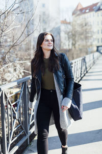 Beautiful young woman walking on footbridge during sunny day