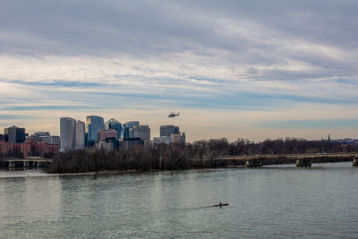 Scenic view of river by buildings against sky