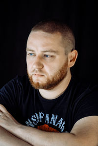 Portrait of young man against black background