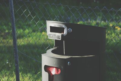 Close-up of dustbin against chainlink fence