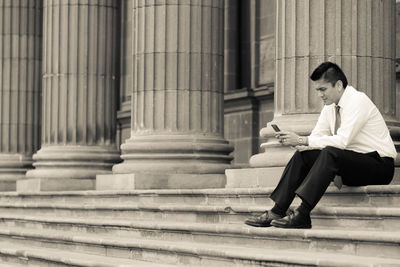 Businessman using smart phone while sitting on steps