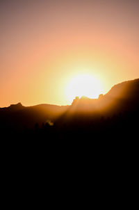 Scenic view of silhouette mountains against orange sky