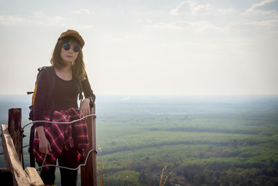 Young woman looking away on land against sky
