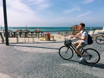 Young man riding bicycle on shore