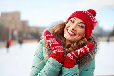 Smiling young woman wearing hat against snow during winter