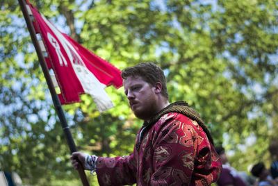 Young man holding flag at palio di legnano against trees