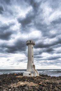 Lighthouse by sea against sky