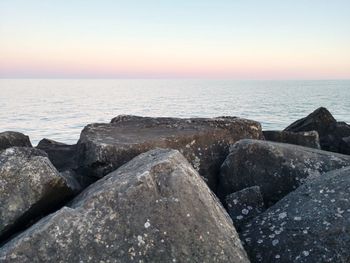 Rocks on sea shore against sky during sunset