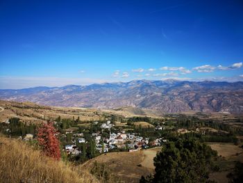 High angle view of landscape and mountains against blue sky