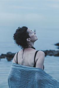 Rear view of woman looking at sky while standing in sea