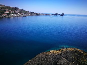 Scenic view of sea by town against clear blue sky