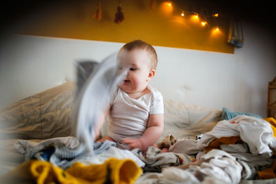 Portrait of cute girl sitting on bed at home