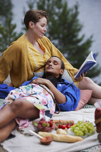 Female couple having picnic and reading book