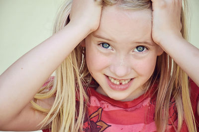 Portrait of girl with hand in hair against wall