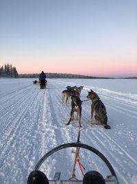 People riding motorcycle on snow covered land against sky