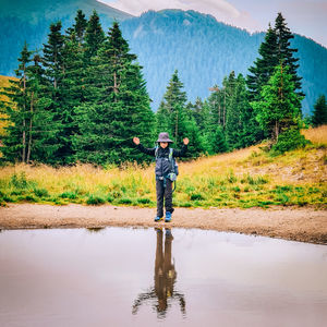 Full length of man standing on tree by water