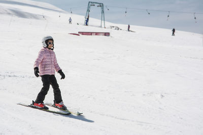 Full length of girl skiing on snow covered landscape