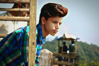 Young man looking away by sky