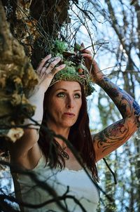 Low angle view of woman standing on tree trunk
