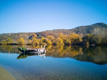 Boat in lake against clear blue sky