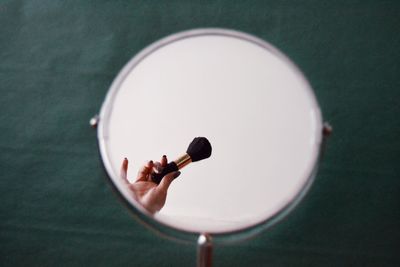 Close-up of woman holding brush reflecting in mirror