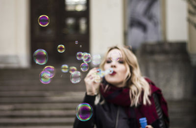 Woman masking bubbles while standing against building