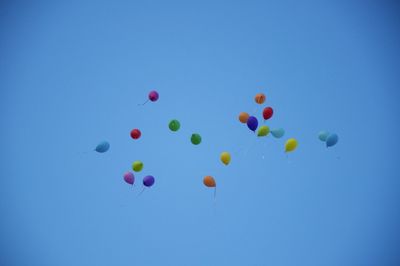 Low angle view of balloons flying against blue sky