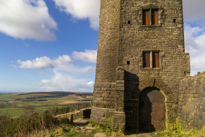 Low angle view of tower against cloudy sky during sunny day