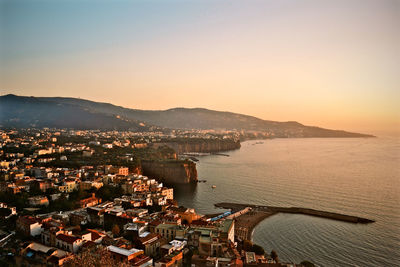 High angle view of townscape by sea against clear sky