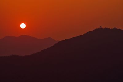 Scenic view of silhouette mountains against orange sky