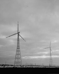 Low angle view of windmills on field against sky