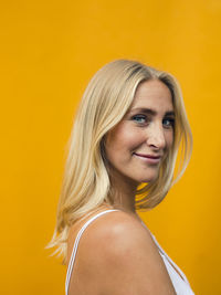 Portrait of smiling woman against yellow background