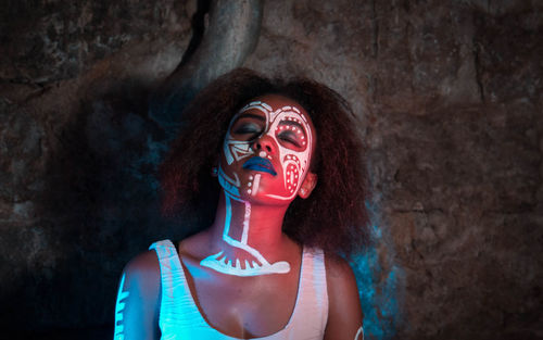 Woman with face paint and closed eyes in cave