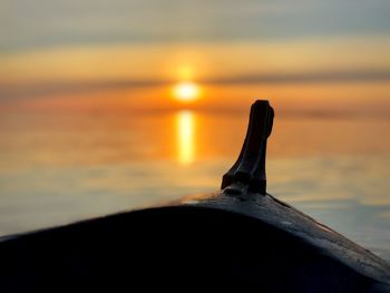 Close-up of metallic structure on beach against sky during sunset