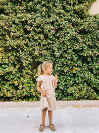 Young woman standing against plants