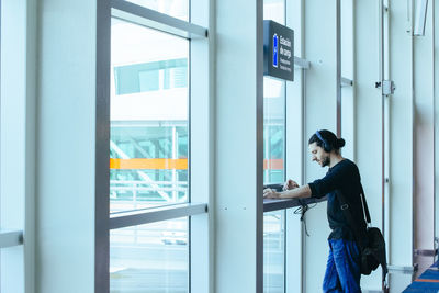 Side view of woman looking through glass window